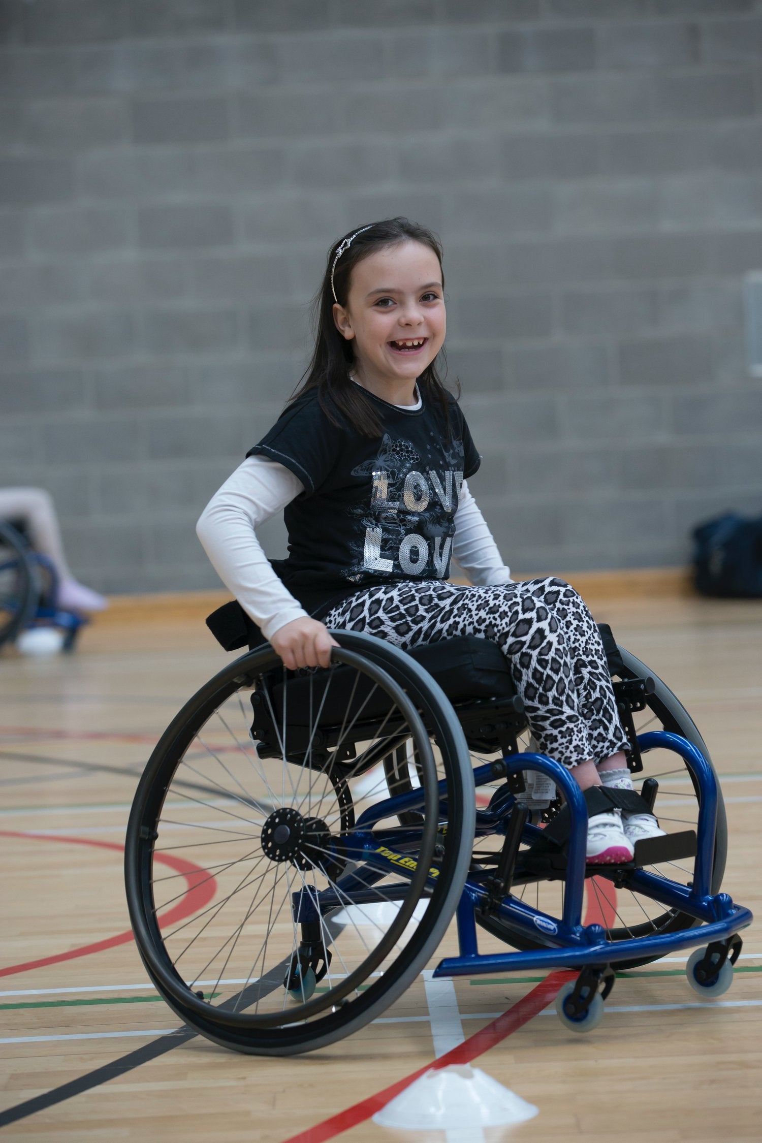 image of a smiling girl in a wheelchair on a basketball court