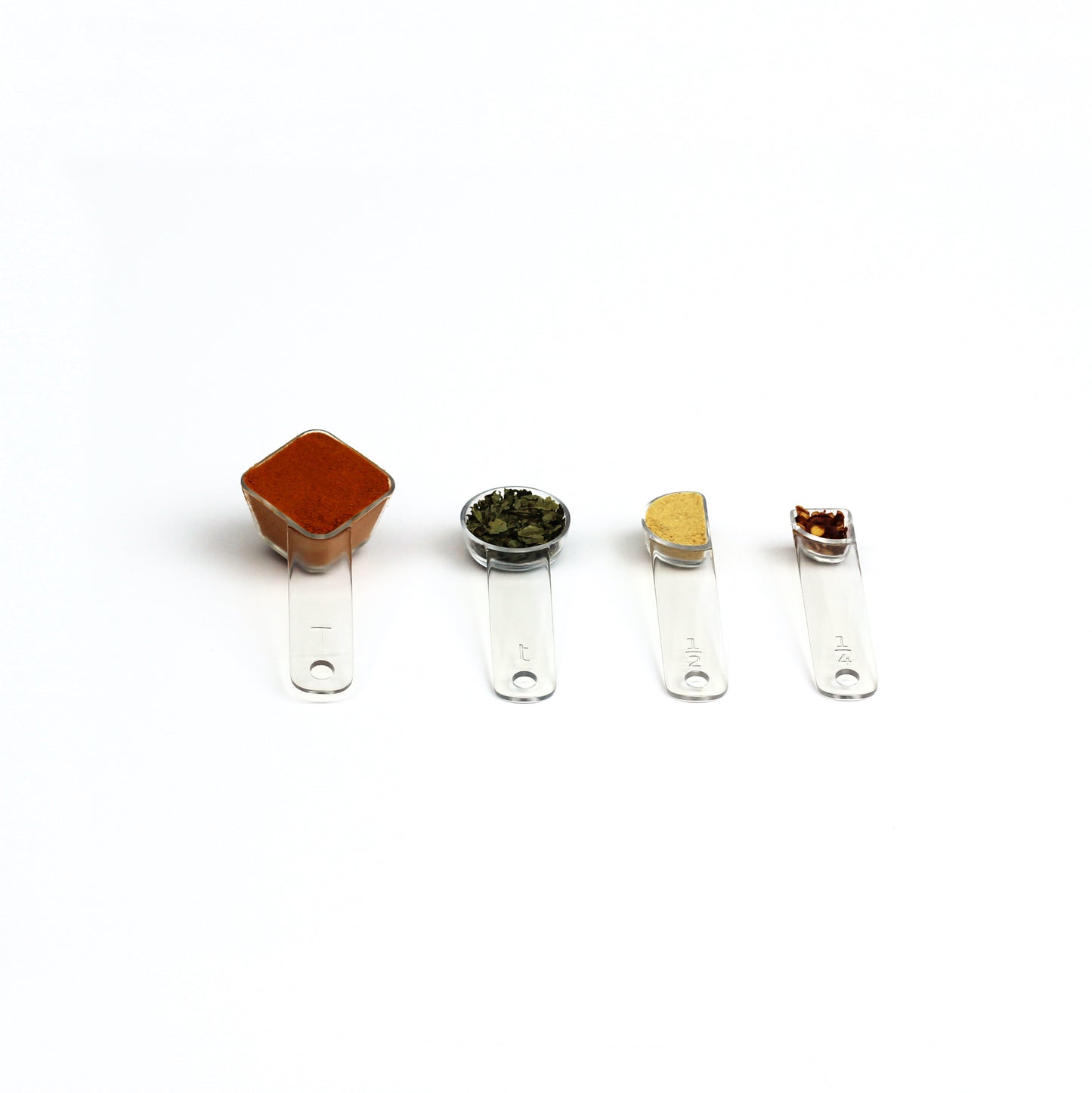 four visual measuring spoons, each a different shape to show the size, are arrayed with colorful spices