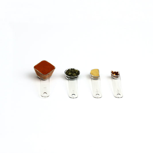 four visual measuring spoons, each a different shape to show the size, are arrayed with colorful spices 