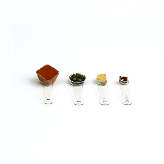 four visual measuring spoons, each a different shape to show the size, are arrayed with colorful spices
