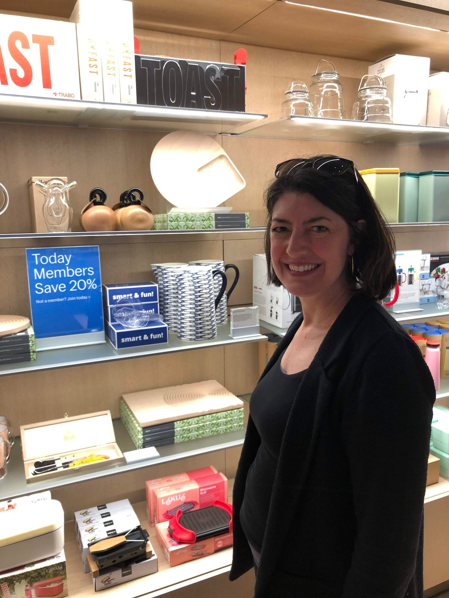 Pam Daniels standing in front of shelves in the MoMA Design Store where Visual Measuring Cups are displayed